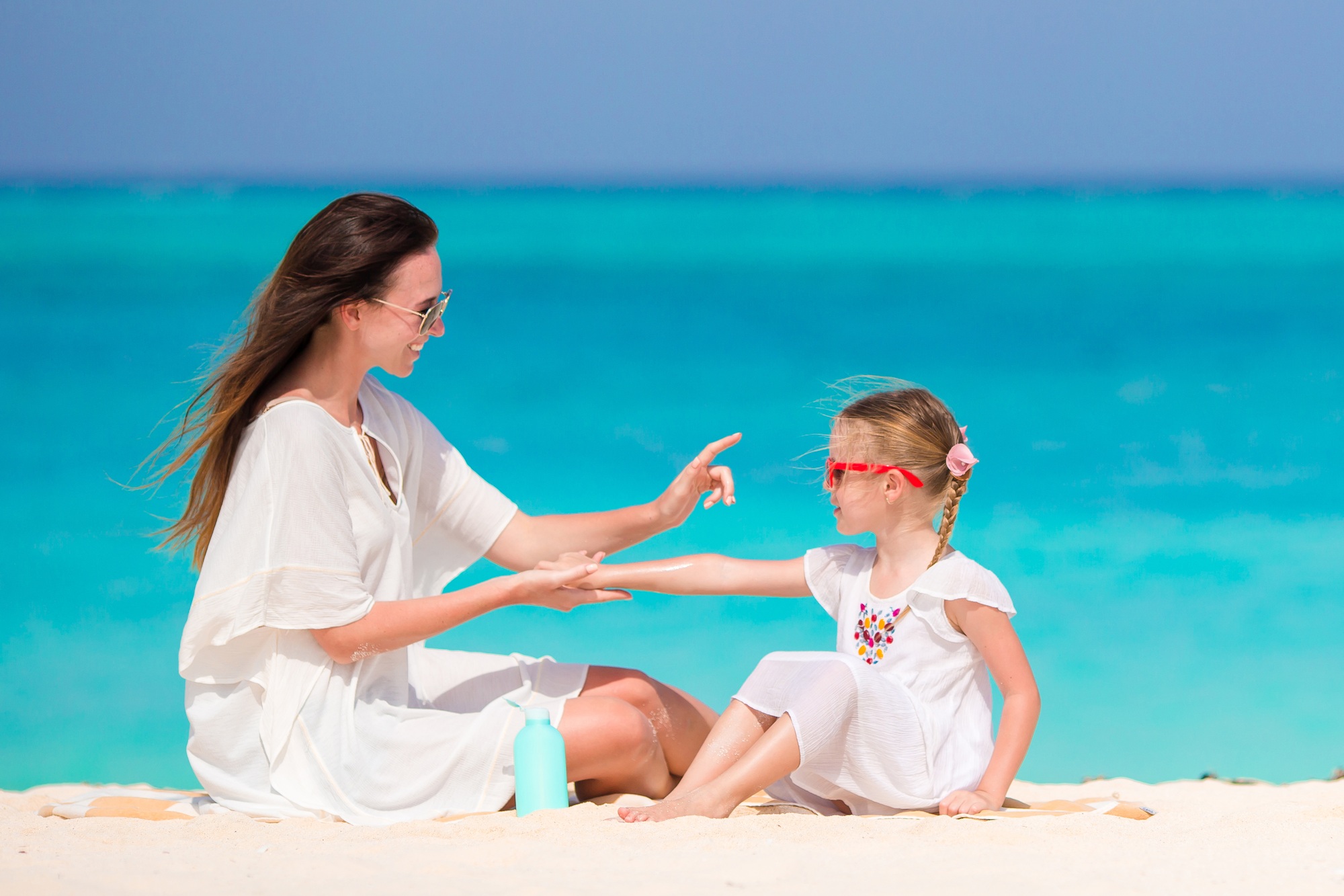Ypung mother applying sun cream to daughter nose